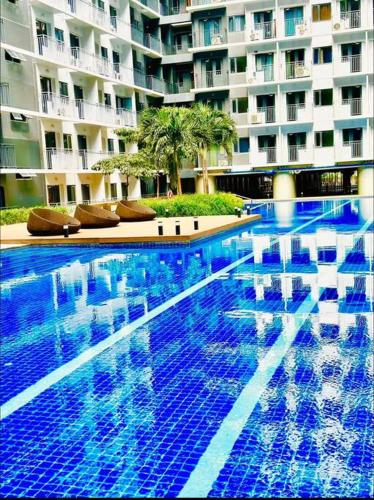 a large blue swimming pool in front of a building at Shabby Chic & Contemporary Condo in Manila