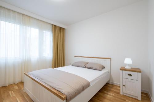 een witte slaapkamer met een bed en een raam bij Filip in Bar