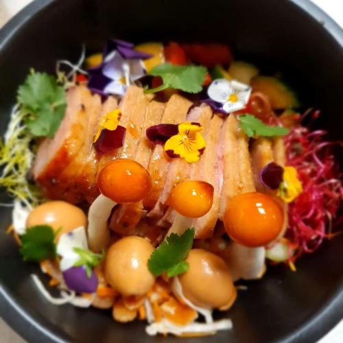 une assiette de nourriture contenant de la viande et des fleurs dans l'établissement La Petite Porte Verte, à Bouilland