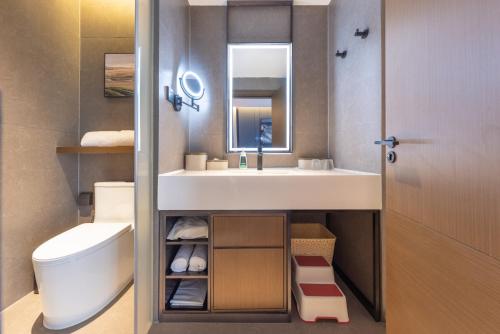 a bathroom with a sink and a toilet and a mirror at Atour Hotel Guangzhou Panyu Wanbo CBD Hanxi Changlong in Guangzhou