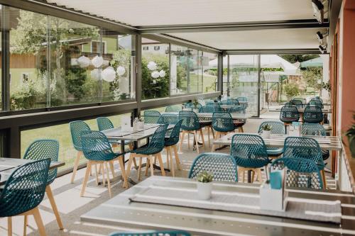 un restaurante con sillas azules, mesas y ventanas en Dorfcafe Unken Hotelpension sWirtshaus im Dorf en Unken