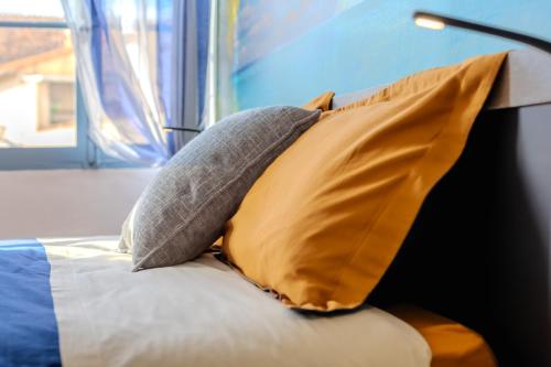 a yellow pillow sitting on a bed with a window at Appartement esprit Tahitien in Rivesaltes