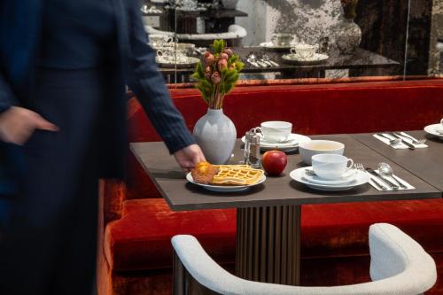 a person is standing near a table with a plate of food at Hotel des Carmes by Malone in Paris
