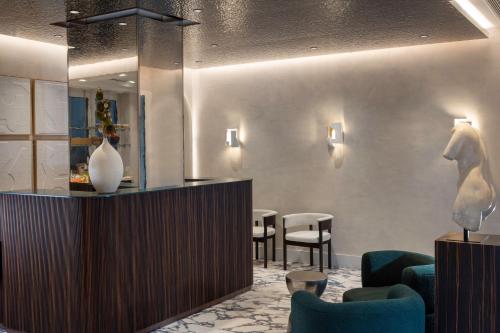 a lobby with a waiting room with chairs and a counter at Hotel des Carmes by Malone in Paris