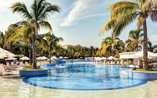- une grande piscine bordée de palmiers et de parasols dans l'établissement Sabbat Mazatlán, à Mazatlán