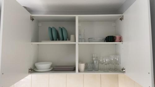 a white cabinet filled with dishes and glasses at Ziemeļblāzma in Rīga