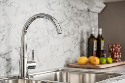 a kitchen sink with a faucet and fruit on a counter at Modern New Stylish Apartment in Åkersberga