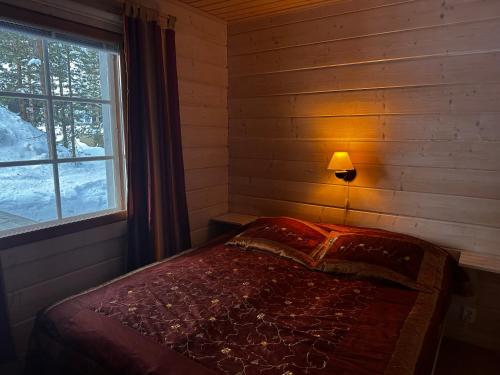 sypialnia z łóżkiem z lampką i oknem w obiekcie Villa Lumia, lomamökki Levillä w mieście Kittilä