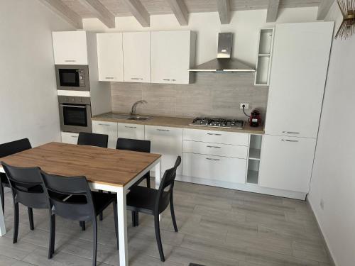 a kitchen with white cabinets and a wooden table and chairs at Villetta 2 La Caletta in La Caletta