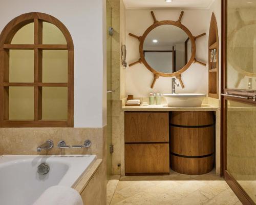 a bathroom with a tub and a sink and a mirror at Grand Hyatt Bali in Nusa Dua