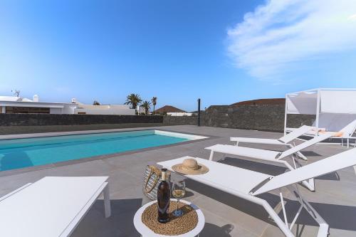 a villa with a swimming pool and white chairs at Vv Villa Secretos de Yaiza 1 by Hh - private pool & BBQ in Yaiza