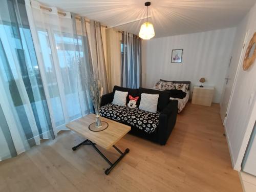 un salon avec un canapé noir et une table dans l'établissement DISNEY - PARIS 5 Min DE DISNEY - PK privé gratuit - 4 personnes - Terrasse jardin, à Chessy
