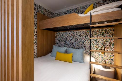 a bedroom with a bunk bed with yellow pillows at Hotel Le Colombier in Colmar