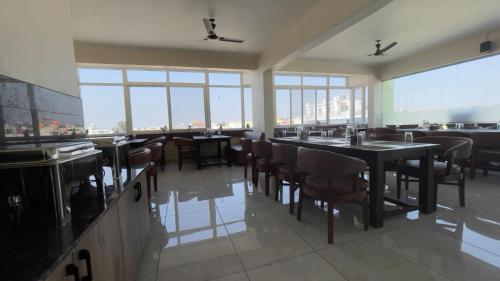 a restaurant with tables and chairs and large windows at Hotel Kinotree Yeshwanthpur in Bengaluru