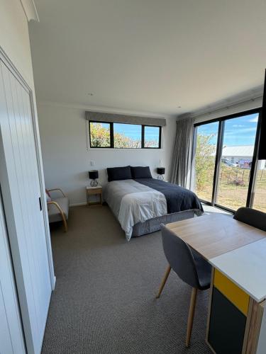 a bedroom with a bed and a table and windows at Cashmere B&B in Masterton