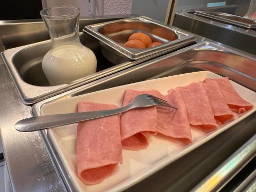 un vassoio con prosciutto, una forchetta e una bottiglia di latte di Le 2 by Hotel Akena - Nantes Beaujoire, Porte de Sainte Luce a Sainte-Luce-sur-Loire