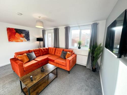 a living room with an orange couch and a table at No.32 by Blue Skies Stays in Bowburn