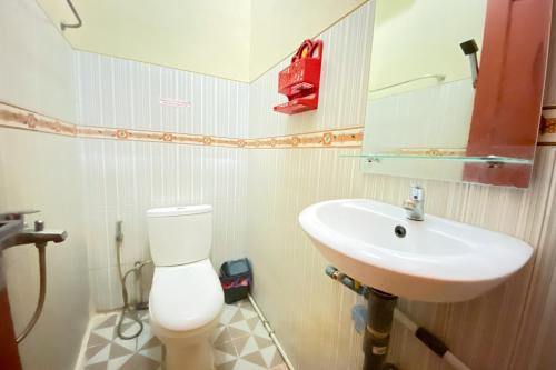 y baño con aseo blanco y lavamanos. en RedDoorz Syariah at D'Rizs Homestay en Bukittinggi