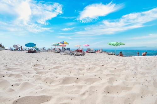 a beach with umbrellas and people sitting on the sand at Privilege Fort Beach Apartments in Sveti Vlas