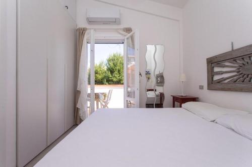 um quarto com uma cama branca e uma porta aberta em M200 - Marcelli, nuovo bilocale a 200mt dal mare em Marcelli