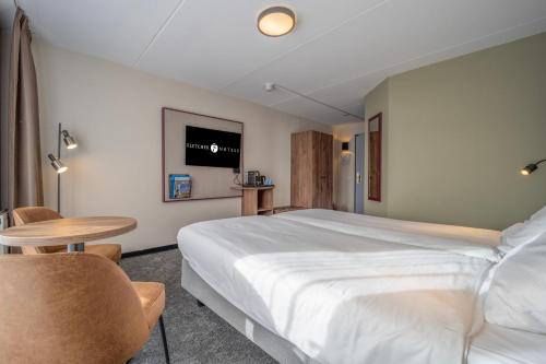 a bedroom with a large bed and a table and chairs at Fletcher Hotel - Restaurant de Zeegser Duinen in Zeegse
