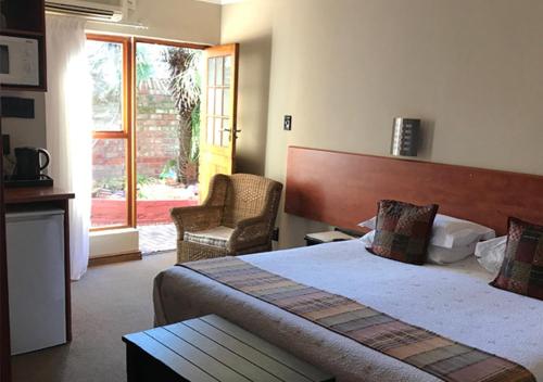 ポートエリザベスにあるA La Martha's Air-Port Guest Houseのベッドと椅子付きのホテルルーム