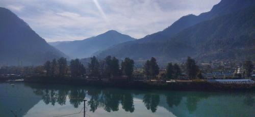 a lake with a town and mountains in the background at Hotel Lake View Paradise in Uttarkāshi