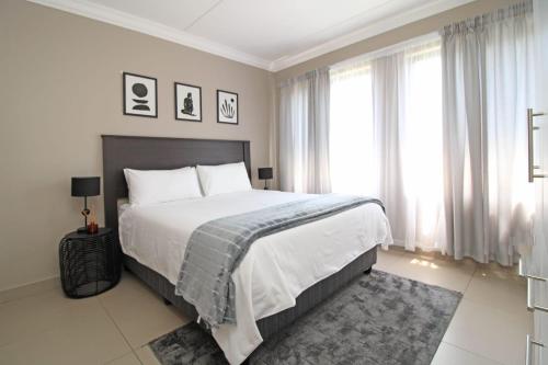 una camera da letto con un grande letto con lenzuola bianche e finestre di New Apartment a Chartwell