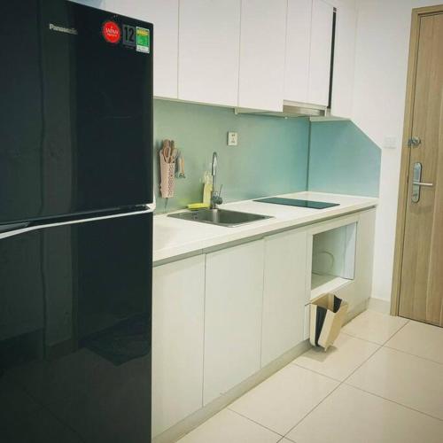 a kitchen with white cabinets and a black refrigerator at Homestay Vinhome Ocean Park S201 in Hanoi