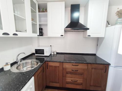 eine Küche mit weißen Schränken und einem Waschbecken in der Unterkunft CASA EL SUEÑO DE ARACENA in Aracena