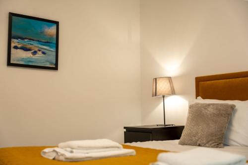 a bedroom with a bed with a lamp and a painting on the wall at Lagavulin Apartment in Oban