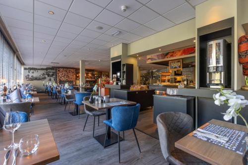 a restaurant with wooden tables and blue chairs at Fletcher Hotel - Restaurant de Zeegser Duinen in Zeegse