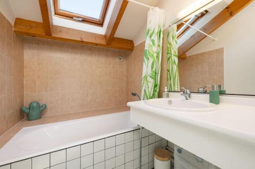 een badkamer met een wastafel, een bad en een raam bij Les Dunes - Duplex - 6 personnes in Jullouville-les-Pins