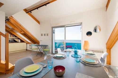 une salle à manger avec une table et une vue sur l'océan dans l'établissement Les Dunes - Duplex - 6 personnes, à Jullouville