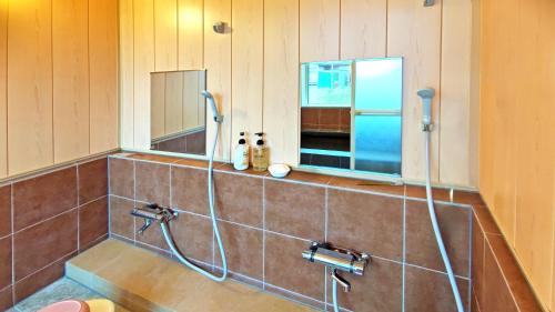 a bathroom with a shower and two mirrors at White House Onsen Guesthouse in Shiraoi