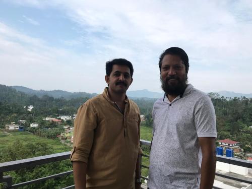 two men standing next to each other on a balcony at Western Ghats Holiday Home in Kalpetta