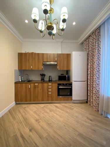 a kitchen with wooden cabinets and a white refrigerator at Жк Riverside in Almaty