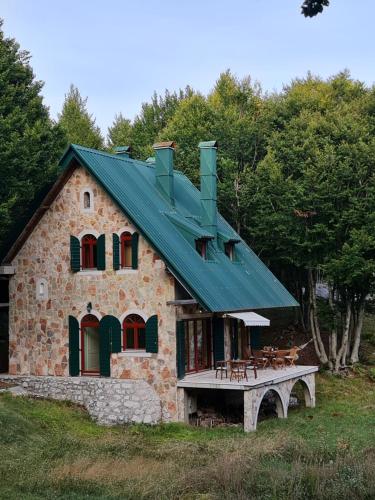 a stone house with a green roof on a field at Lovćen Escape, Rustric House in Cetinje