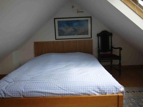sypialnia z łóżkiem i krzesłem na poddaszu w obiekcie Maisonnette - Centre Landerneau w mieście Landerneau