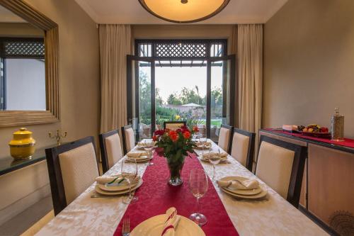a dining room table with a vase of flowers on it at Luxury Villa GoldPalm Marrakech in Marrakech
