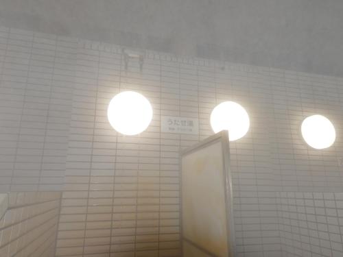 a bathroom with three lights on a wall with a mirror at HigashimaeOnsen Shinwanoyu Hotel Akitaya in Hokuto