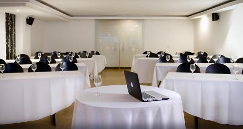a room with white tables and chairs with a laptop on it at Hotel Silver Javeriana By Hospedium Bogota in Bogotá