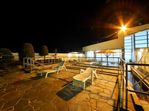 a patio with two chairs and an umbrella at night at HigashimaeOnsen Shinwanoyu Hotel Akitaya in Hokuto
