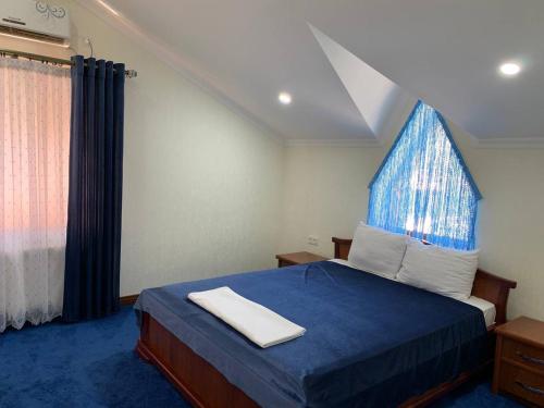 a bedroom with a blue bed and a window at Sunny Breeze in Karakkulʼtugay