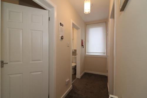 La salle de bains est pourvue de toilettes et d'une porte blanche. dans l'établissement Signature - Bruce Terrace Upper - Blantyre, à High Blantyre