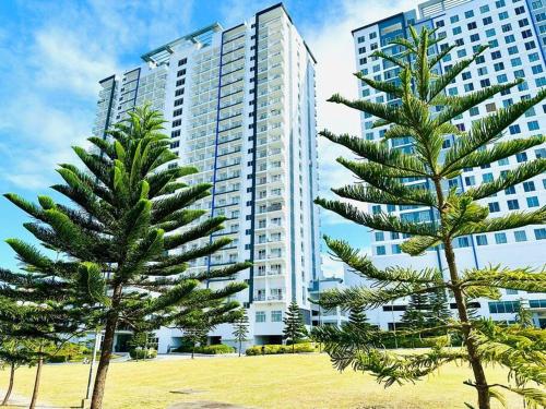 two palm trees in front of a large building at Cool and Savvy 1BR @Cool Suites Tagaytay in Tagaytay