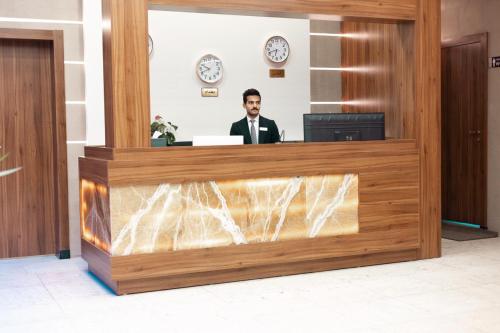 Un uomo è seduto alla reception di Villa Hotel Basra a Bassora