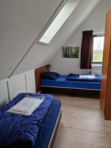a attic room with two beds and a window at Recreatiepark De Tien Heugten in Schoonloo