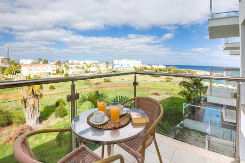 een tafel en stoelen op een balkon met uitzicht op de oceaan bij Apartment Austin - Coralli Beachfront Resort in Protaras