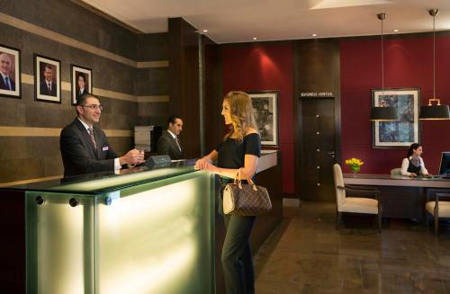 a woman standing at a counter in a lobby at Crowne Plaza Amman by IHG in Amman